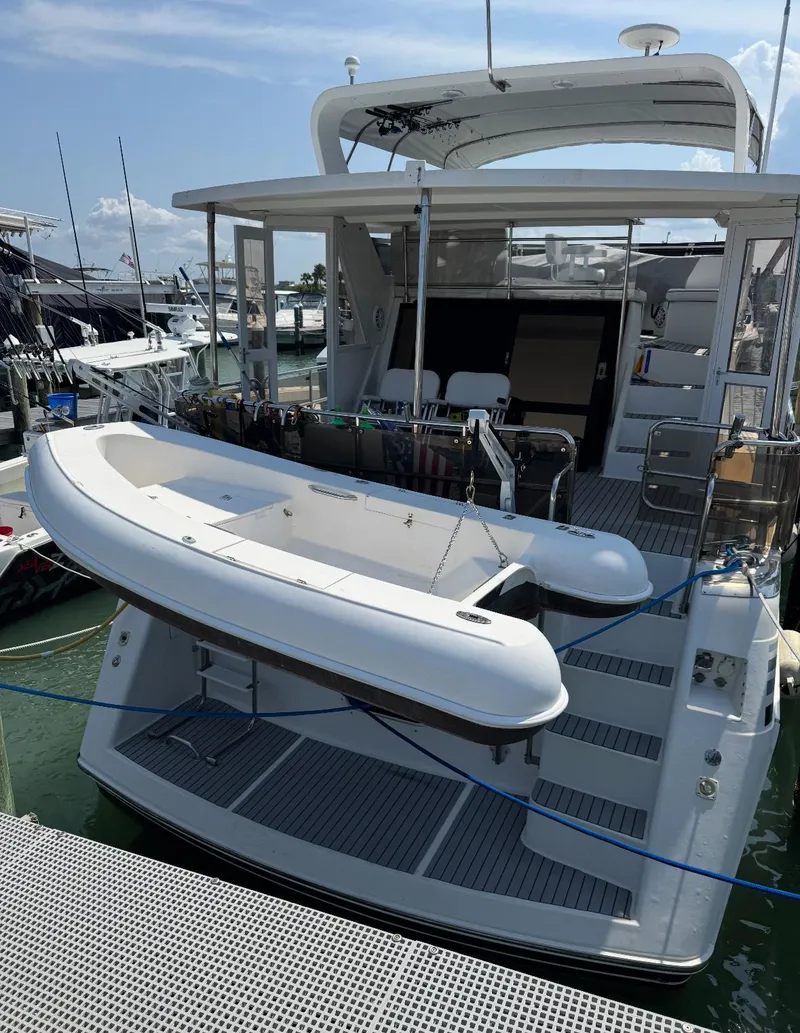 Slide: The Image of 1994 President 445 Sundeck yacht docked in a marina, featuring a spacious deck and American flag. - 2