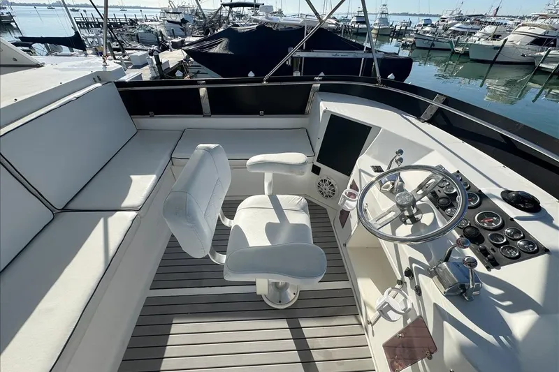 Slide: The Image of 1994 President 445 Sundeck yacht helm with white seating and control panel, docked at marina. - 38