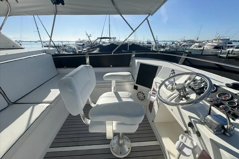 Slide: The Image of 1994 President 445 Sundeck yacht helm with white seating and steering wheel, docked at marina. - 39