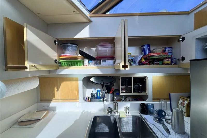 Slide: The Image of 1994 President 445 Sundeck kitchen with open cabinets, sink, and various kitchen items. - 93