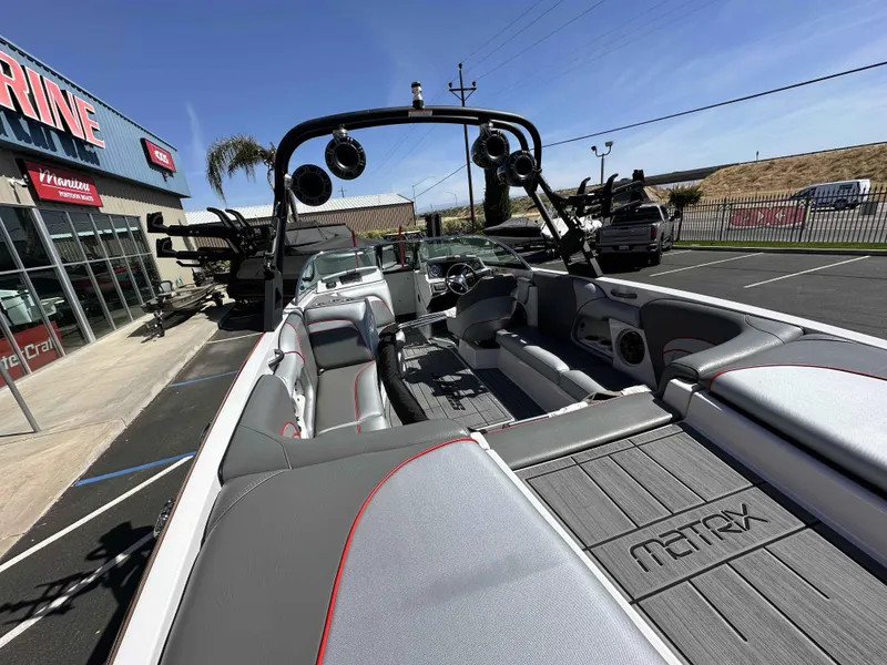 Slide: The Image of 2024 Sanger 231 SL boat interior with gray seating and Matrix flooring, parked outside a marine store. - 7