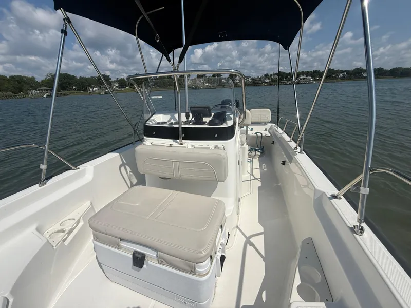 Slide: The Image of 2022 Boston Whaler 170 Montauk boat interior with seating and canopy on a calm lake. - 11