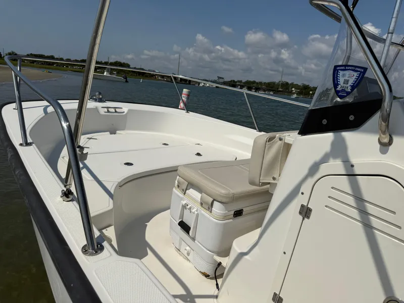 Slide: The Image of 2022 Boston Whaler 170 Montauk boat interior with seating, docked by the shore under a clear sky. - 15