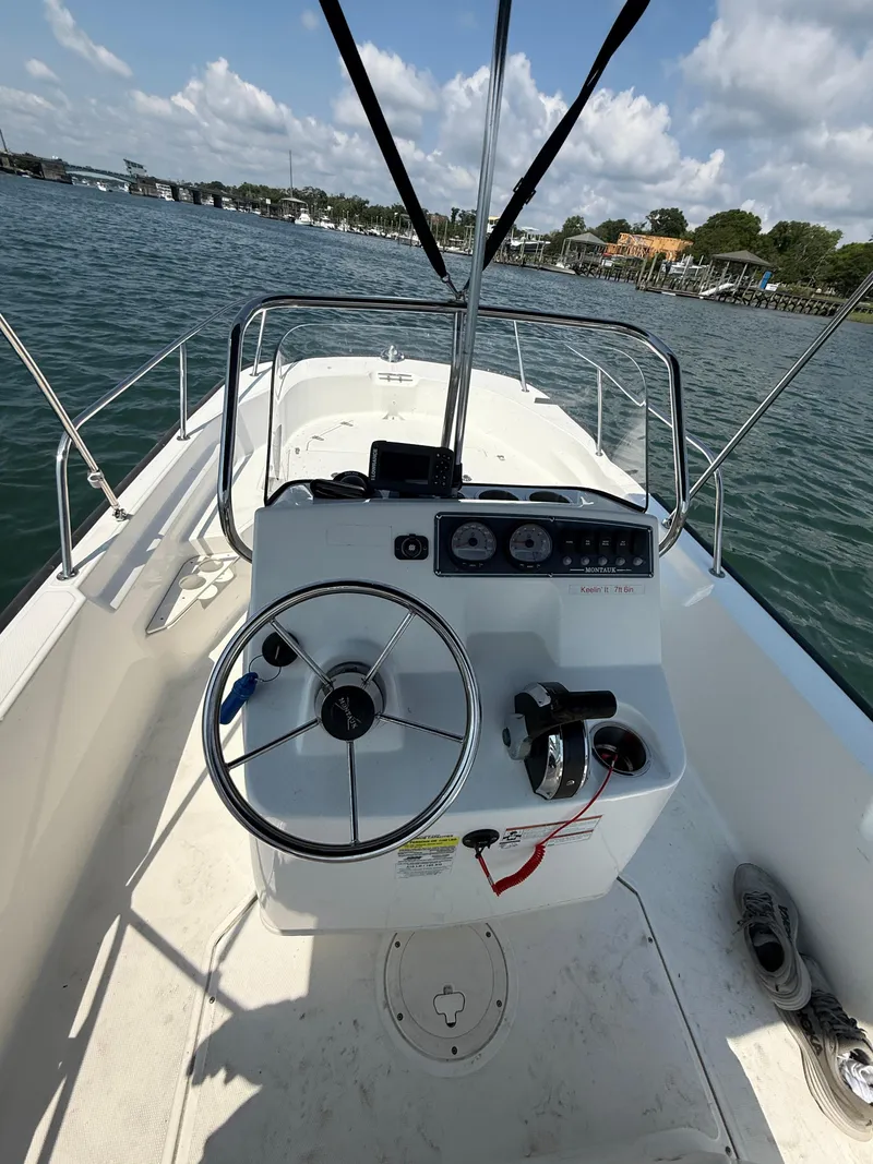 Slide: The Image of 2022 Boston Whaler 170 Montauk boat interior with steering wheel and controls on open water. - 23