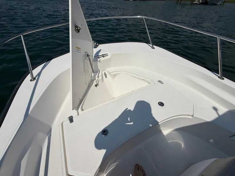 Slide: The Image of 2022 Boston Whaler 170 Montauk boat interior with open storage compartment on calm water. - 8