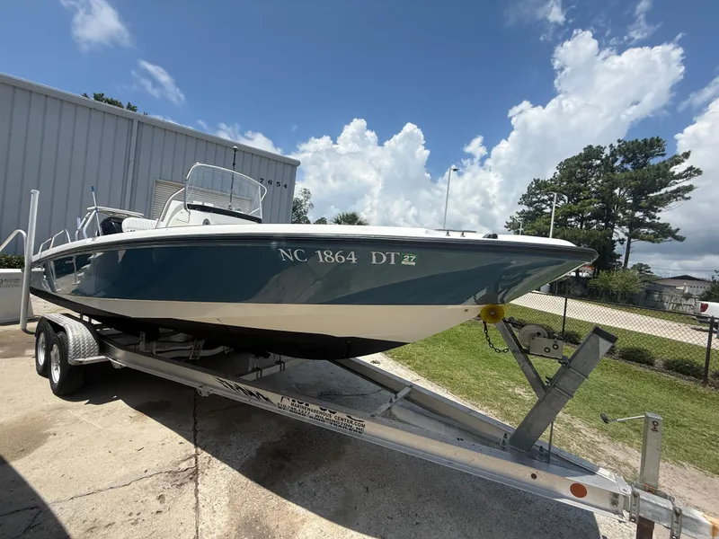 Slide: The Image of 2011 Boston Whaler 230 Dauntless boat on trailer, parked outdoors under a cloudy sky. - 11