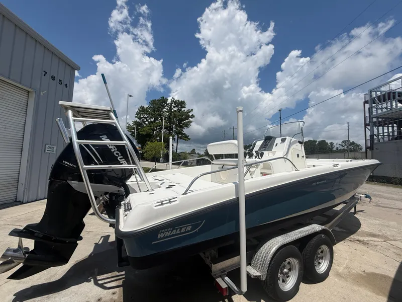 Slide: The Image of 2011 Boston Whaler 230 Dauntless boat on trailer, parked outdoors under a cloudy sky. - 3