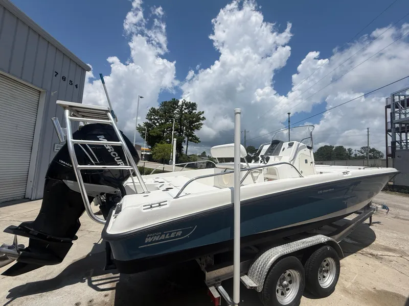 Slide: The Image of 2011 Boston Whaler 230 Dauntless boat on trailer, parked outdoors under a cloudy sky. - 4