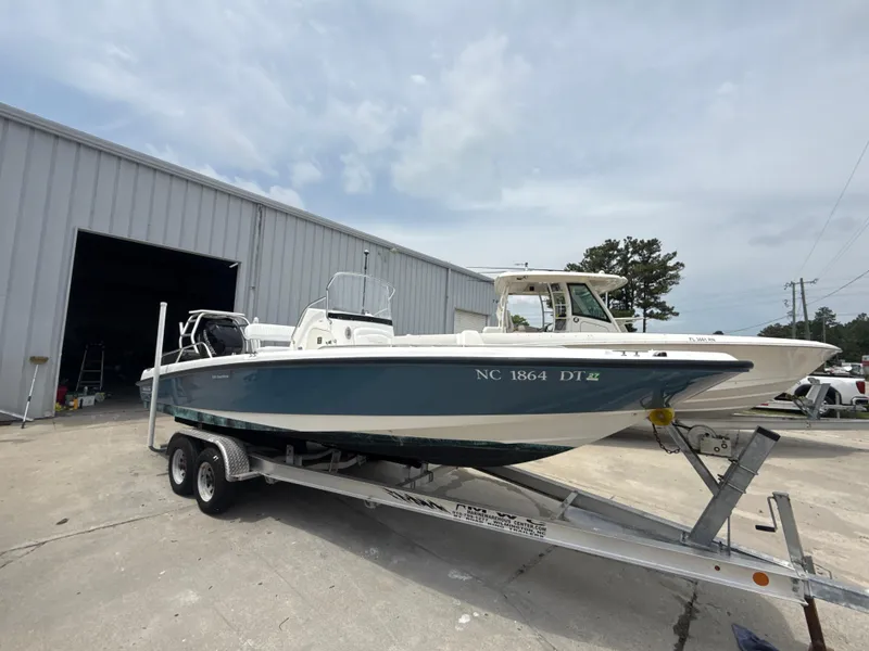 Slide: The Image of 2011 Boston Whaler 230 Dauntless boat on trailer outside a large garage. - 8