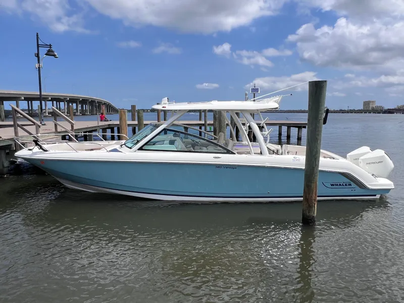 Slide: The Image of 2022 Boston Whaler 320 Vantage boat docked, light blue hull, clear sky background. - 12