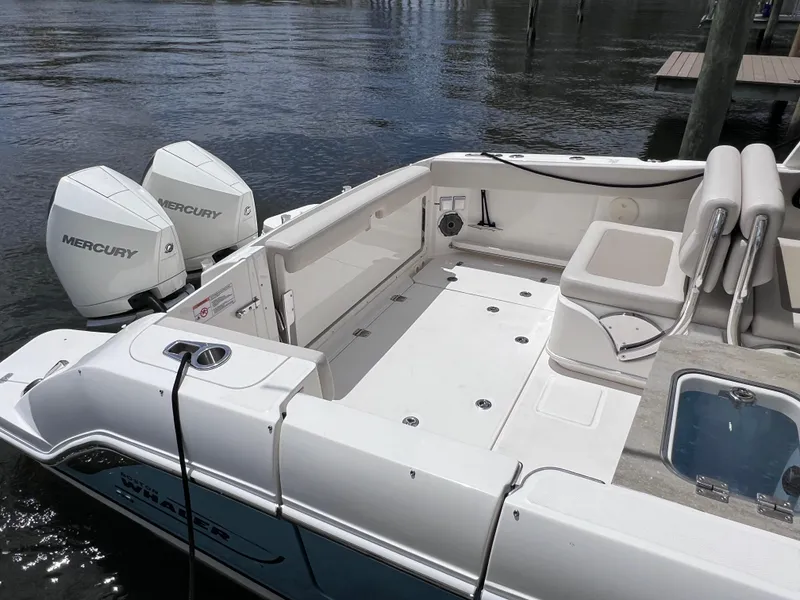 Slide: The Image of 2022 Boston Whaler 320 Vantage boat with Mercury engines, docked on calm water. - 16