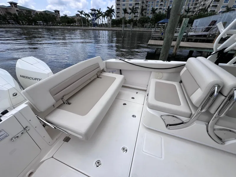 Slide: The Image of 2022 Boston Whaler 320 Vantage boat interior with seating, docked by waterfront. - 22