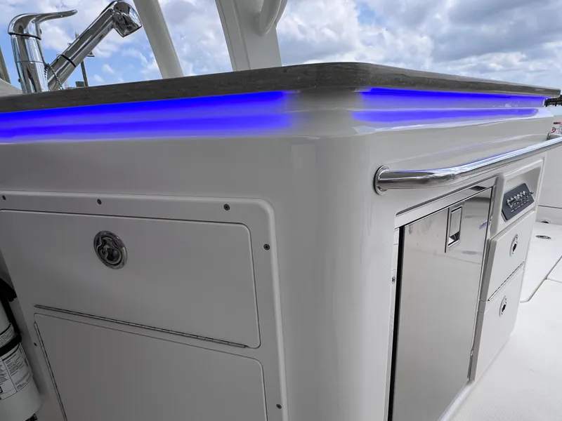 Slide: The Image of 2022 Boston Whaler 320 Vantage boat interior with blue LED lighting and storage compartments. - 43