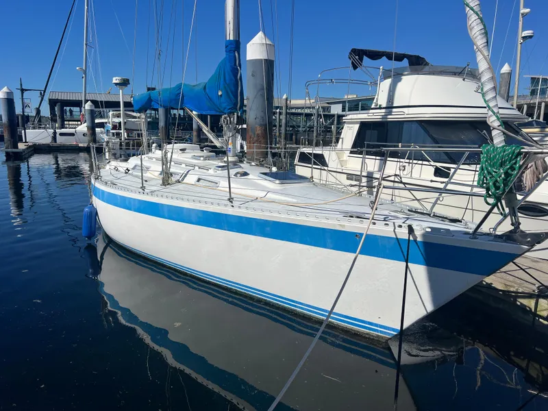 Slide: The Image of 1985 Wauquiez Pretorian Sloop docked at marina, featuring blue and white hull. - 10