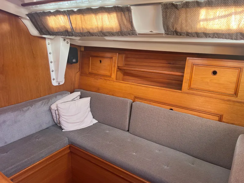 Slide: The Image of Interior of 1985 Wauquiez Pretorian Sloop with wooden cabinetry and gray upholstered seating. - 15