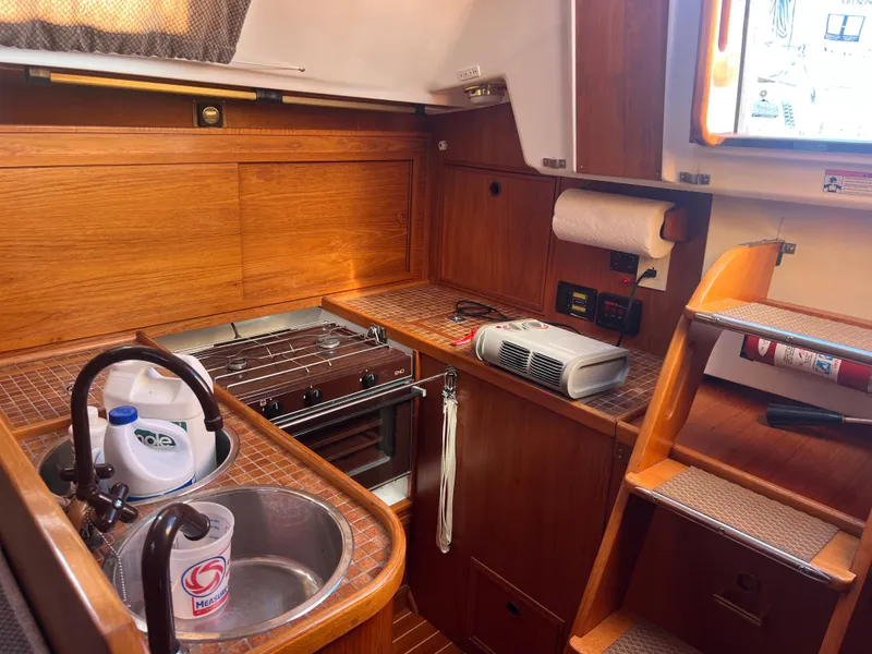 Slide: The Image of 1985 Wauquiez Pretorian Sloop interior kitchen with sink, stove, and wooden cabinetry. - 16