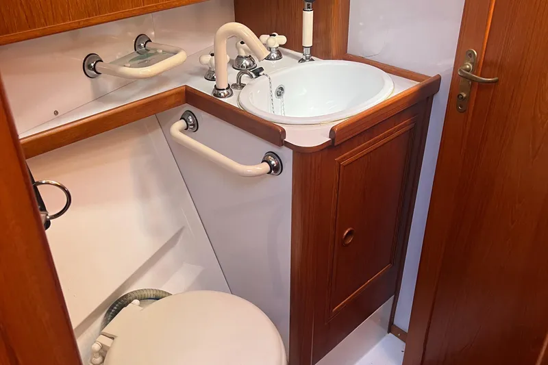 Slide: The Image of 1985 Wauquiez Pretorian Sloop bathroom with wooden cabinetry and white fixtures. - 17