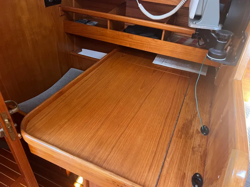 Slide: The Image of 1985 Wauquiez Pretorian Sloop interior with wooden navigation desk and storage shelves. - 18