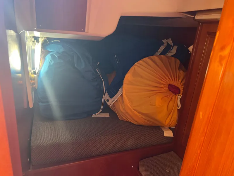 Slide: The Image of Interior of 1985 Wauquiez Pretorian Sloop with storage bags on a cushioned bench. - 19