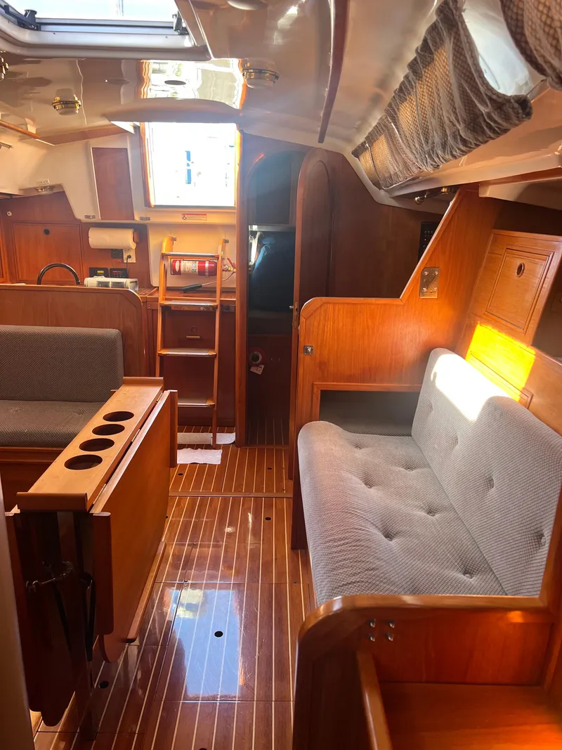 Slide: The Image of Interior of 1985 Wauquiez Pretorian Sloop, featuring wooden finishes and cozy seating. - 25