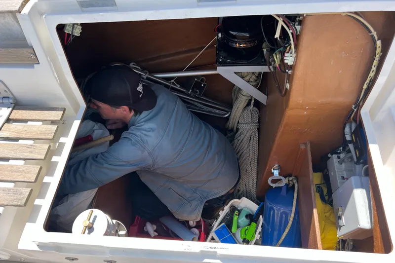 Slide: The Image of Man working in the storage compartment of a 1985 Wauquiez Pretorien Sloop sailboat. - 38