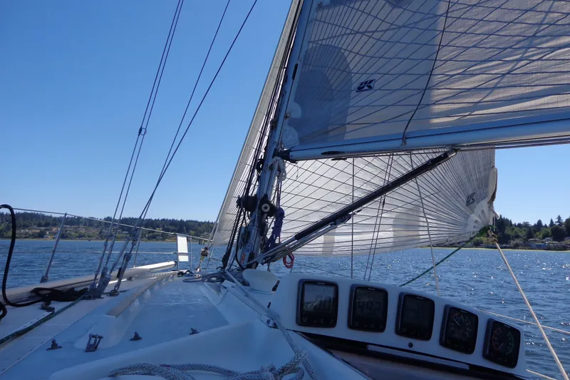 Slide: The Image of 1985 Wauquiez Pretorien Masthead sailboat on open water, clear sky, and lush shoreline. - 42