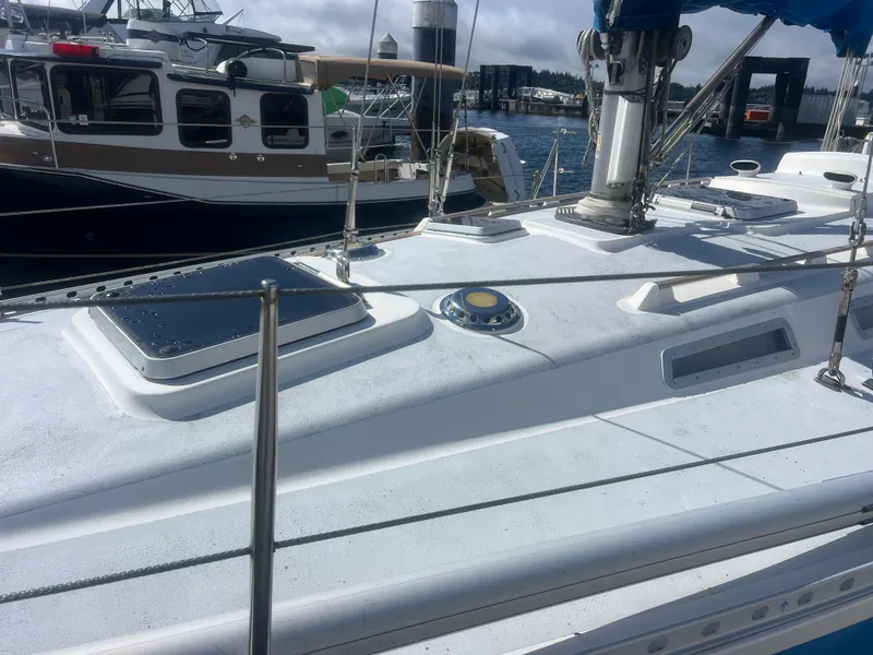 Slide: The Image of 1985 Wauquiez Pretorian Sloop deck view at marina, showcasing sleek design and rigging. - 5