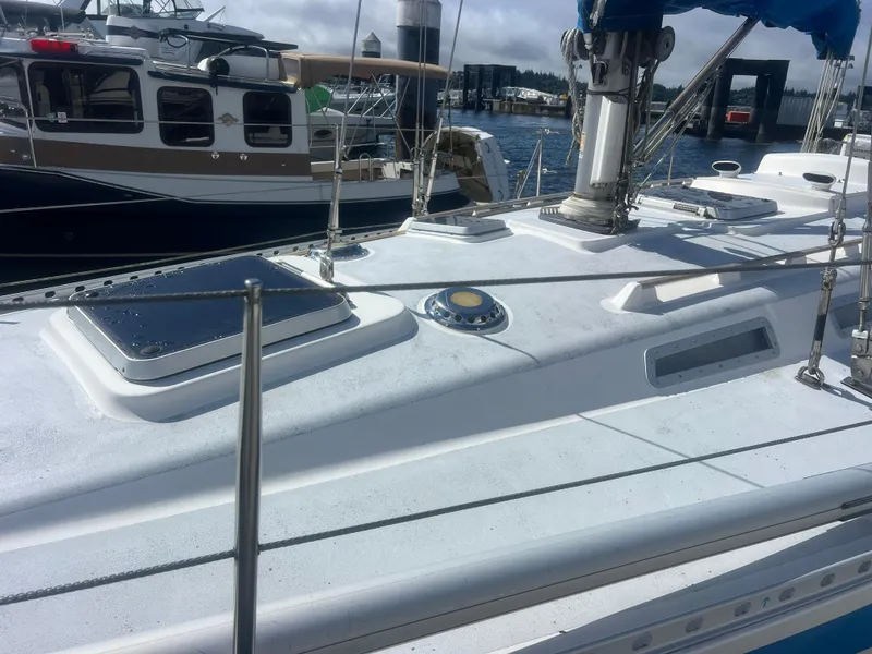 Slide: The Image of 1985 Wauquiez Pretorian Sloop deck view at marina, showcasing sleek design and rigging. - 7