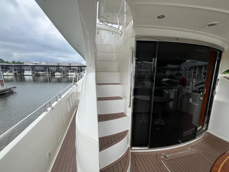 Slide: The Image of 2004 Marquis 59 yacht with sleek exterior, docked at marina, featuring elegant staircase and glass doors. - 2