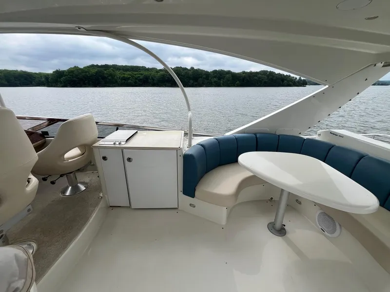 Slide: The Image of 2004 Marquis 59 yacht interior with seating area and table, overlooking a serene lake. - 25