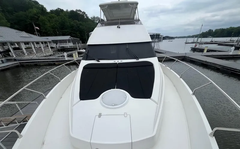 Slide: The Image of 2004 Marquis 59 yacht docked at a marina, surrounded by calm waters and lush greenery. - 28