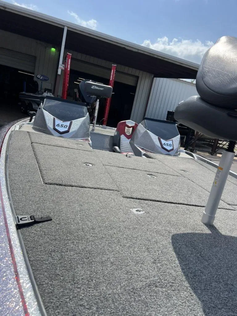Slide: The Image of 2022 Blazer 650 Pro Tour boat with carpeted deck and seating, parked outdoors. - 34