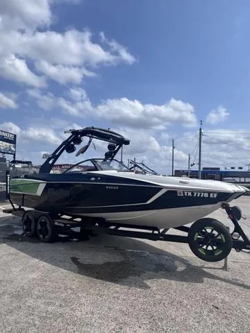 Slide: The Image of 2018 Malibu 24 MXZ boat on trailer under a partly cloudy sky. - 11