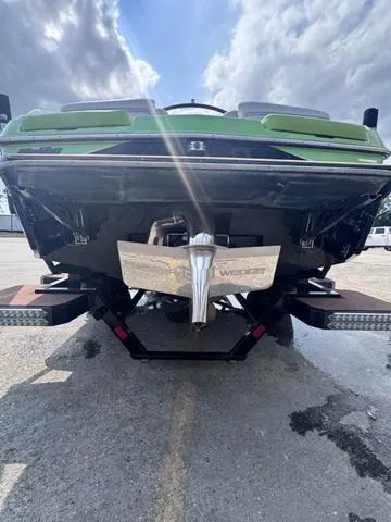 Slide: The Image of 2018 Malibu 24 MXZ boat rear view with green accents under cloudy sky. - 8