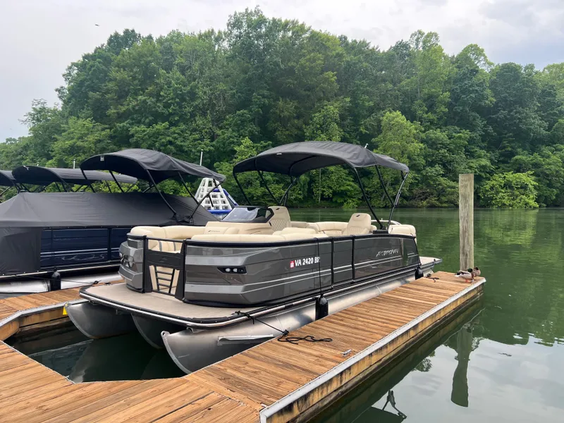 The Image of 2025 Starcraft RX 23 R DC pontoon boat docked on a serene lake. - 1