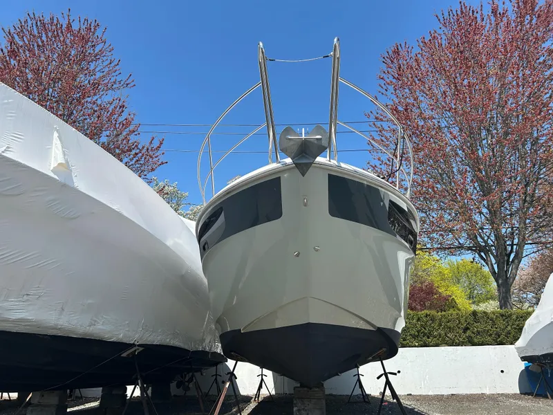 Slide: The Image of 2017 Bavaria S36 Coupe boat on land, surrounded by trees and other boats. - 12