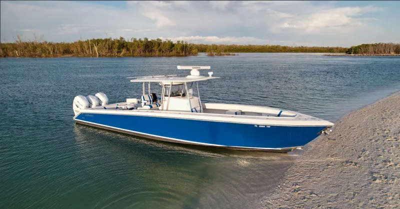 The Image of 2016 Venture 39 Forward Seating boat in serene waters near a sandy shore. - 0