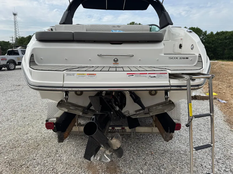 Slide: The Image of 2025 Sea Ray SDX 270 Surf boat rear view with ladder on gravel. - 3