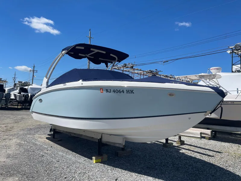 Slide: The Image of 2016 Cobalt R5 boat on display, blue hull, covered, sunny day, gravel lot. - 0