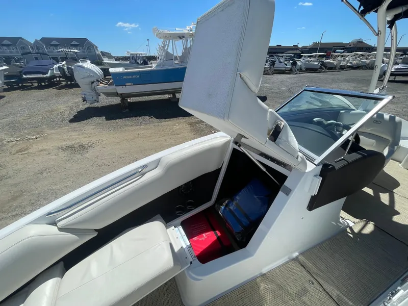 Slide: The Image of 2016 Cobalt R5 boat interior with open storage compartment, white seating, and clear windshield. - 14