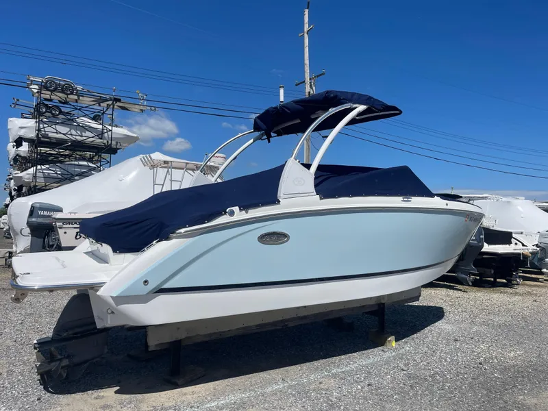 Slide: The Image of 2016 Cobalt R5 boat with blue cover, parked on gravel lot under clear sky. - 2
