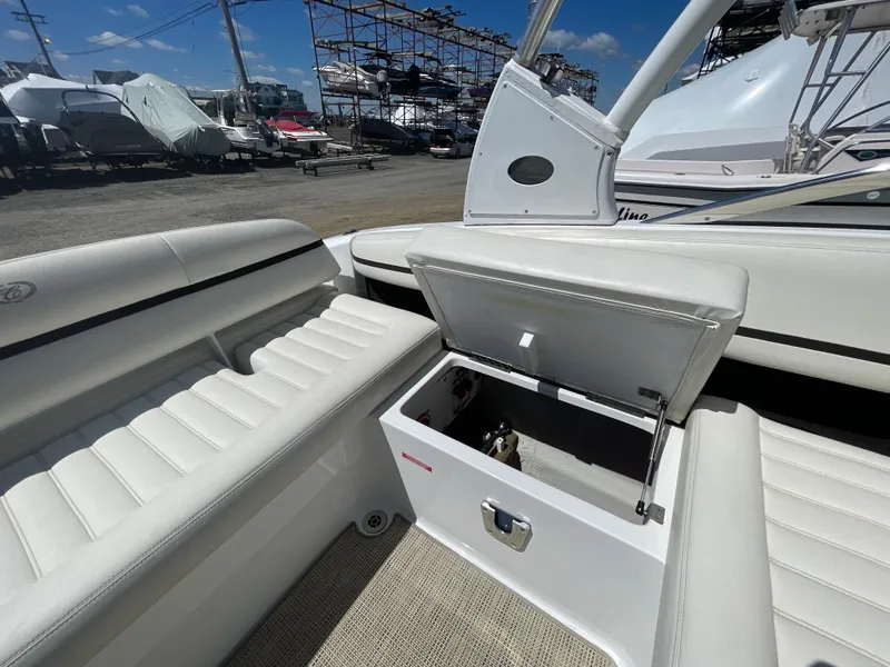Slide: The Image of 2016 Cobalt R5 boat interior with open storage compartment, white seating, and marina background. - 33