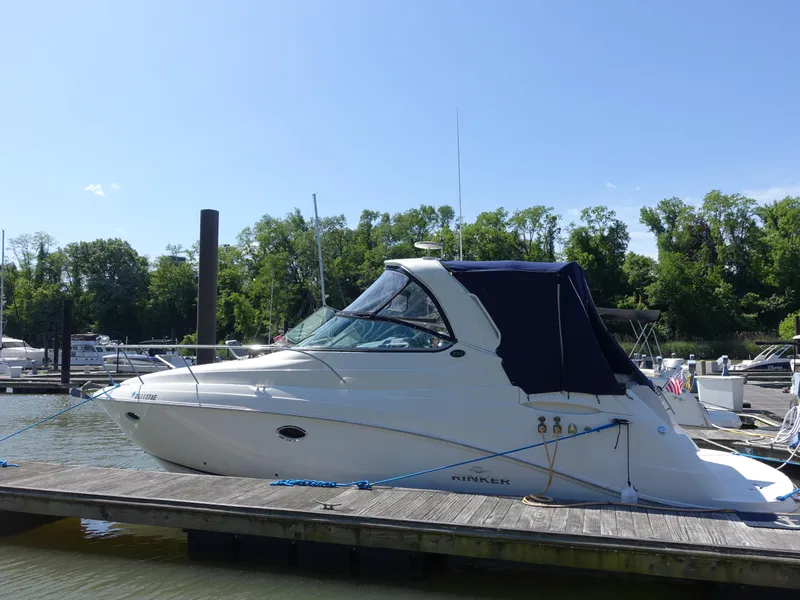 Slide: The Image of 2008 Rinker 330 Express Cruiser docked at a marina, surrounded by trees and boats. - 0