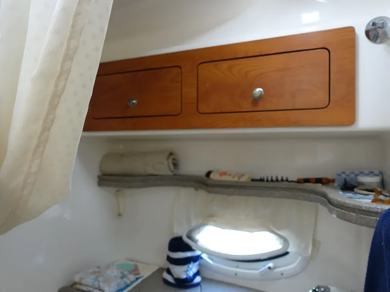 Slide: The Image of 2008 Rinker 330 Express Cruiser cabin interior with wooden cabinets and porthole. - 10