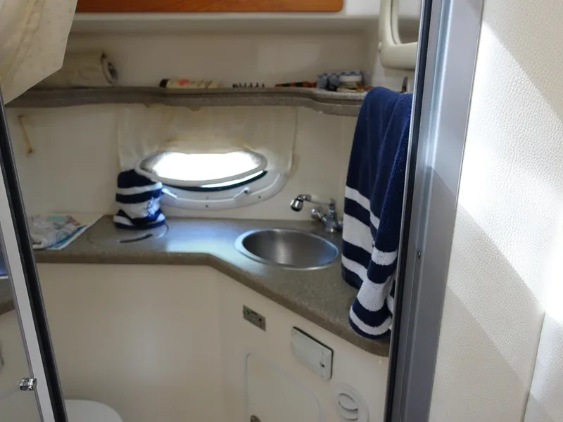 Slide: The Image of 2008 Rinker 330 Express Cruiser bathroom with sink, porthole, and striped towel. - 12