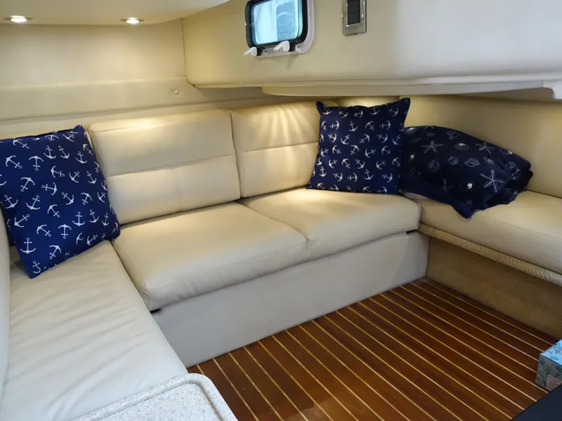 Slide: The Image of 2008 Rinker 330 Express Cruiser interior with beige seating and nautical-themed pillows. - 13
