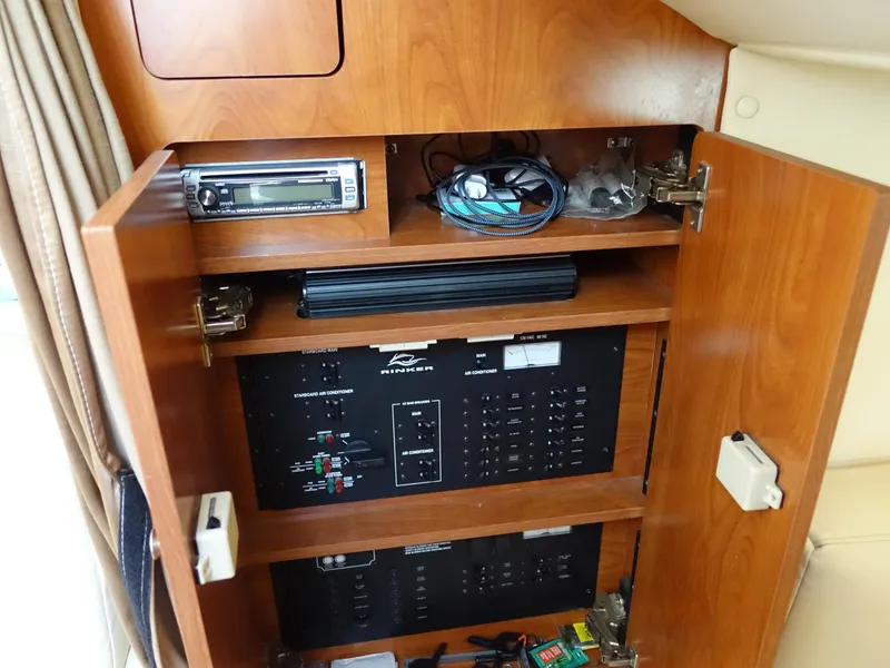 Slide: The Image of 2008 Rinker 330 Express Cruiser interior cabinet with electronic equipment and storage shelves. - 15