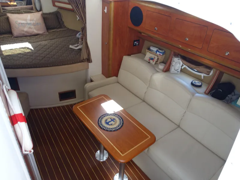 Slide: The Image of 2008 Rinker 330 Express Cruiser interior with sofa, table, and cozy sleeping area. - 2