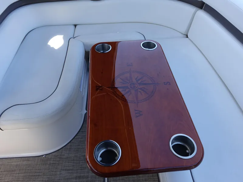 Slide: The Image of 2008 Rinker 330 Express Cruiser interior with compass-themed wooden table and cushioned seating. - 24
