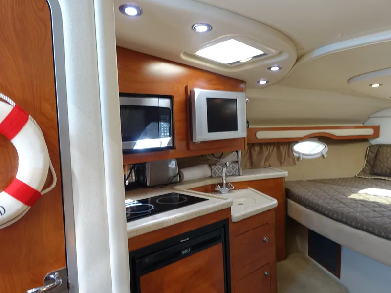 Slide: The Image of 2008 Rinker 330 Express Cruiser interior with kitchenette, microwave, and cozy sleeping area. - 4